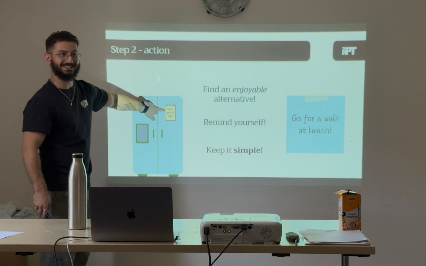 Zak presenting to a room, talking through a slide on taking action.
