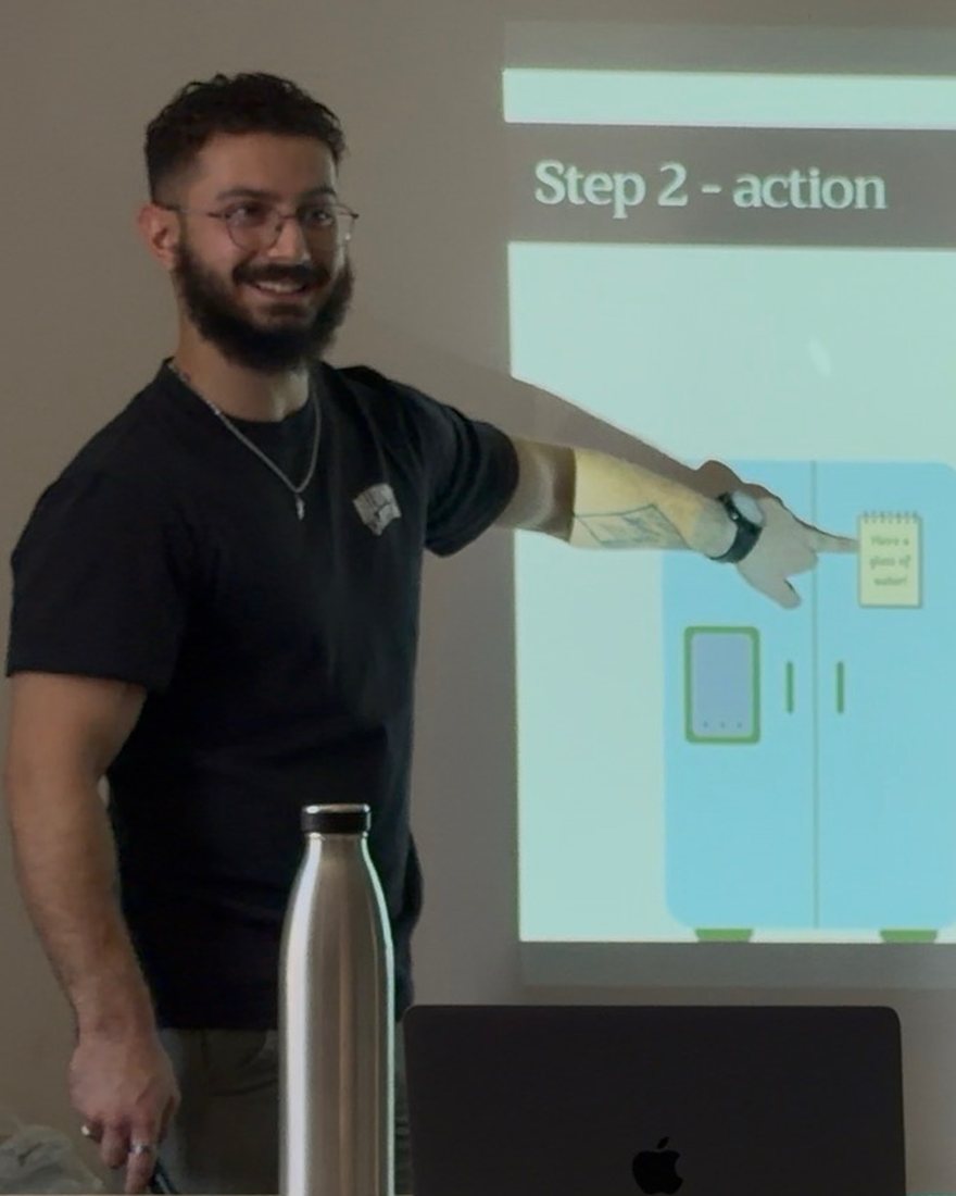 Zak delivering a workshop session, pointing to a slide headed &ldquo;Step 2 &mdash; action&rdquo;.